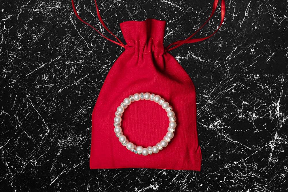 Referenzbild eines Perlenarmbandes auf rotem Beutel aus Samt